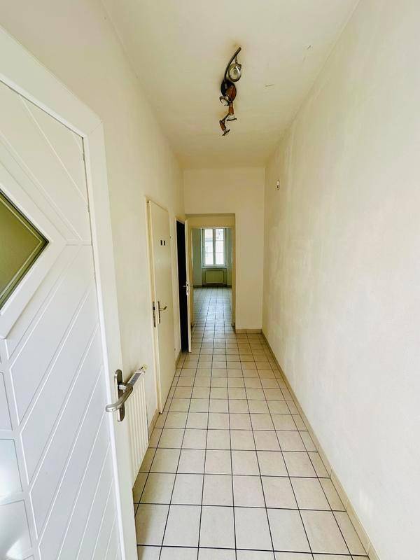 Langer Flur mit Fliesenboden und Zugang zu verschiedenen Zimmern der Wohnung.