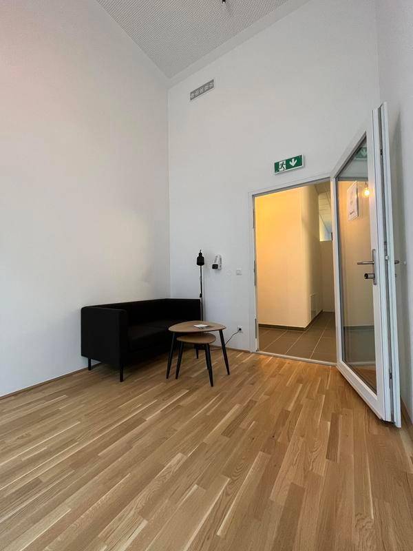 Geräumiger Wohnraum mit hohen Decken, Holzboden und einer modernen Couch, die zu einem offenen Bereich führt.