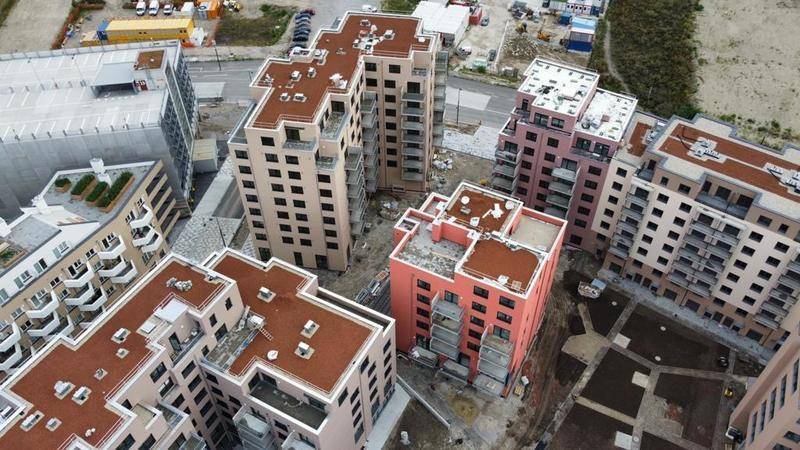 Luftaufnahme eines modernen Wohnkomplexes mit mehreren Neubauten und Baustellenbereichen.