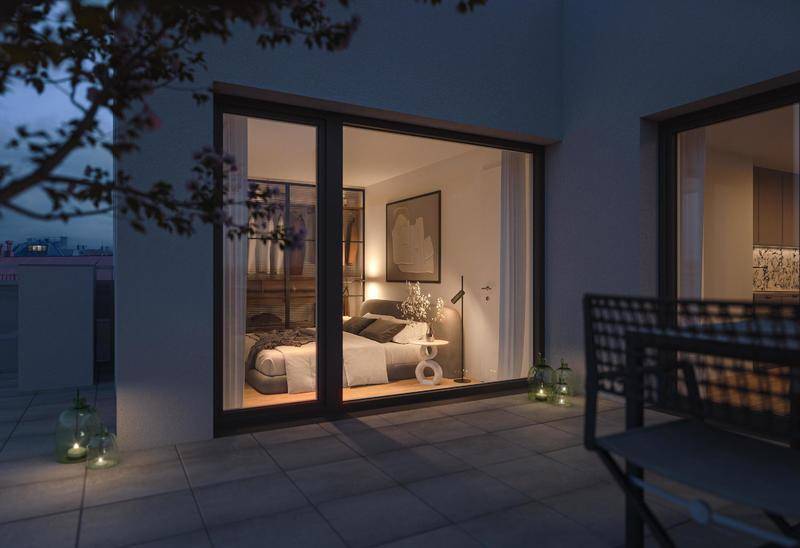 Schlafzimmer mit großen Fenstern und Zugang zu einer Terrasse, stimmungsvoll beleuchtet am Abend.