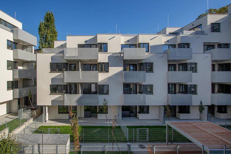 Fassade eines Neubaus mit vielen Balkonen und einem begrünten Innenhofbereich.