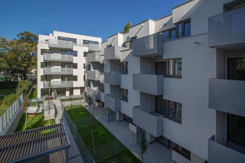 Moderne Wohnanlage mit mehreren Balkonen und einer gepflegten Grünfläche im Innenhof.