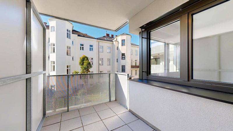 Geräumiger Balkon mit Fliesenboden und moderner Glasbrüstung, bietet einen Stadtblick.