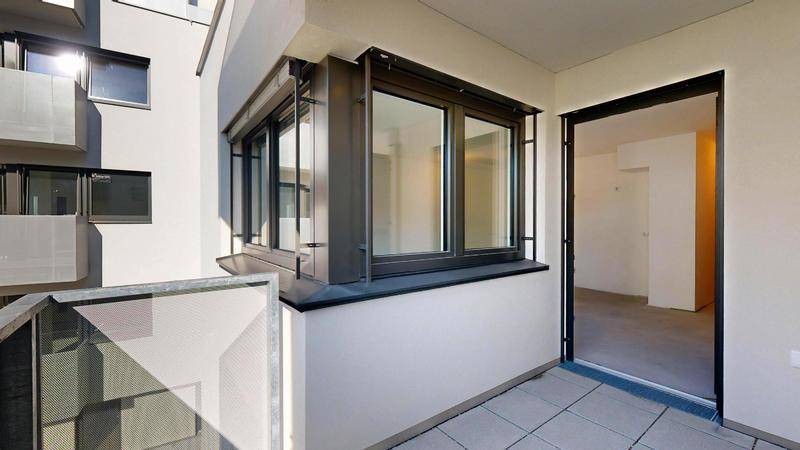 Heller Balkon mit Fliesenboden und Blick auf die umliegenden Gebäude.