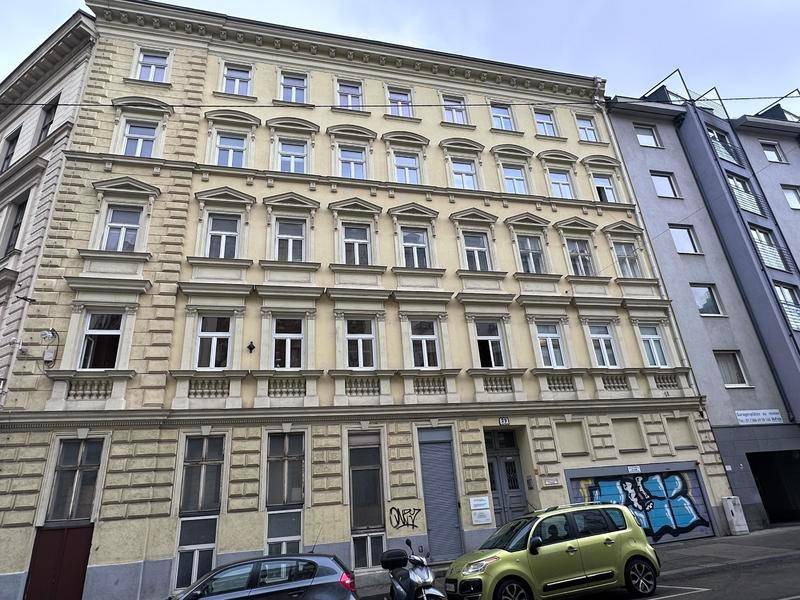 Klassische Altbaufassade mit vielen Fenstern und dekorativen Elementen an einer Stadtstraße.