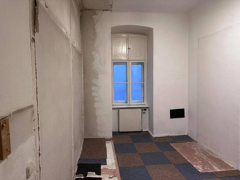 Raum in Renovierungszustand mit gemustertem Boden und einem Fenster, das auf Sanierung wartet.