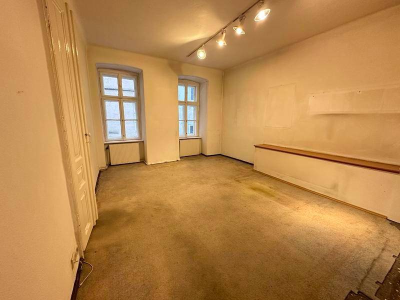 Geräumiger Raum mit Teppichboden, hohen Decken und einer Nische, die auf Renovierung wartet.