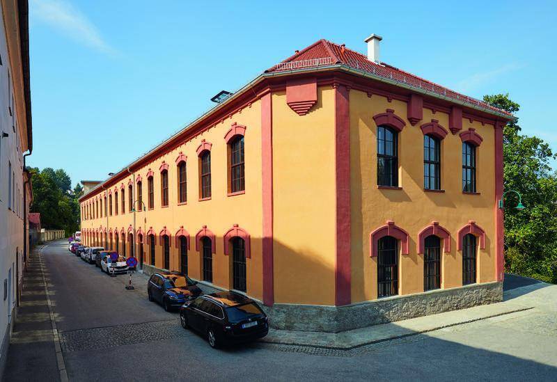 Historisches Gebäude mit markanter gelb-roter Fassade und vielen Fenstern.