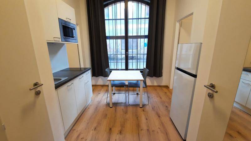 Funktionale Küchenzeile mit Essbereich und Kühlschrank, ideal für kleine Wohnungen.