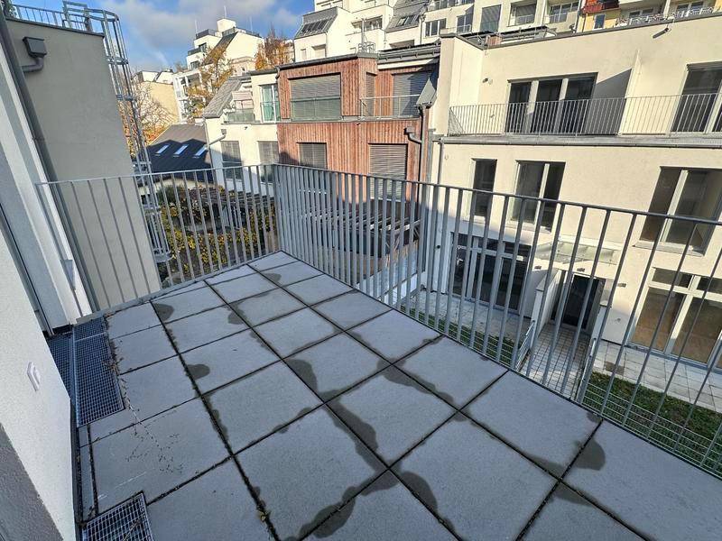 Geräumige Terrasse mit Fliesenboden und Blick auf die umliegenden Gebäude.