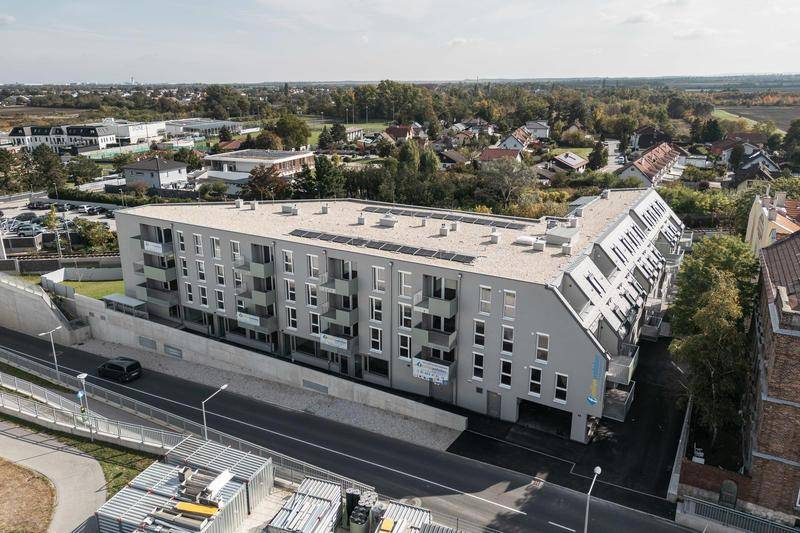 Luftaufnahme des modernen Wohnkomplexes in ländlicher Umgebung mit Photovoltaikanlage auf dem Dach.