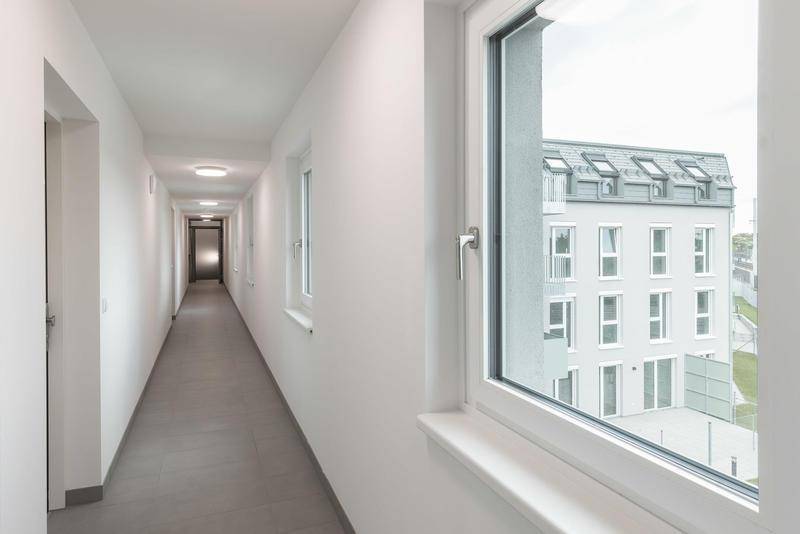 Langer, heller Flur mit Fenster und Blick auf das gegenüberliegende Gebäude.