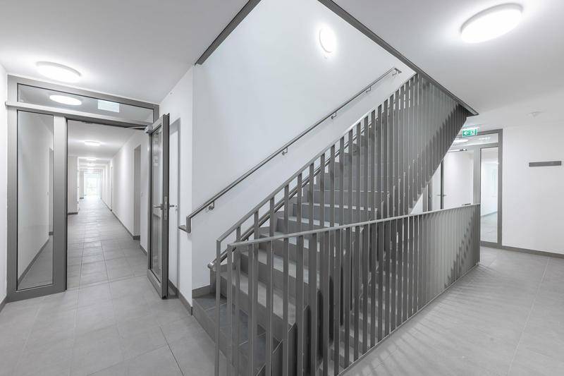 Modernes Treppenhaus mit Metallgeländer und Fliesenboden im Gemeinschaftsbereich des Gebäudes.