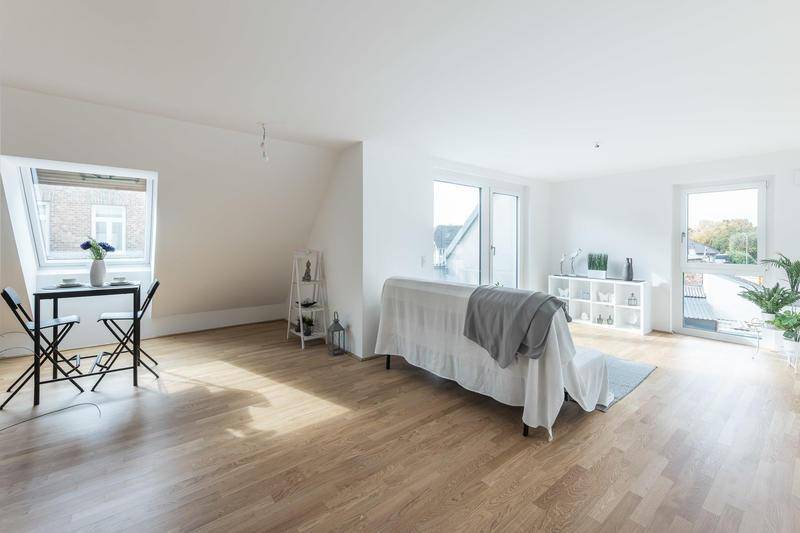 Heller Wohnbereich mit Holzboden, weißen Wänden und Zugang zu einer Terrasse, ergänzt durch ein Dachfenster.