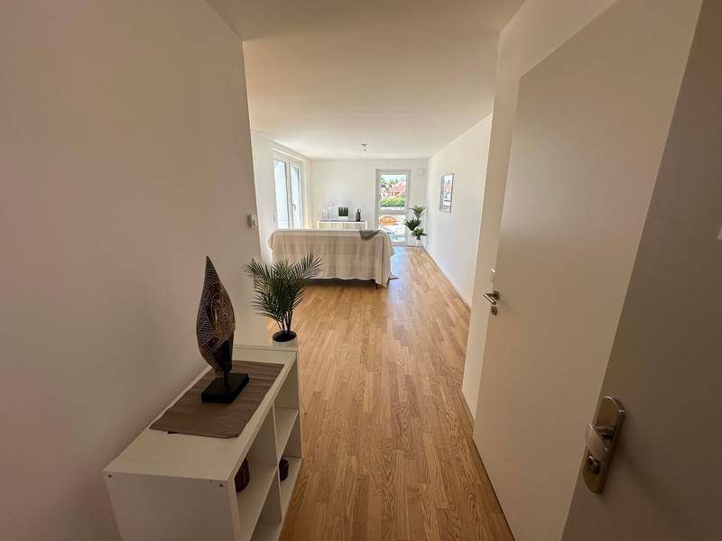 Heller Eingangsbereich mit Holzboden, der in den offenen Wohnbereich der Wohnung führt.