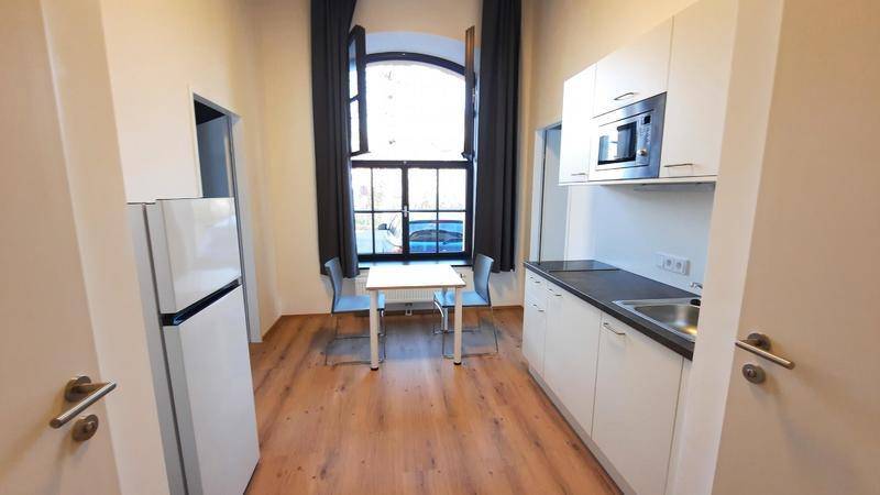 Funktionale Küchenzeile mit Essbereich, Kühlschrank und Fenster in einem hellen Raum.