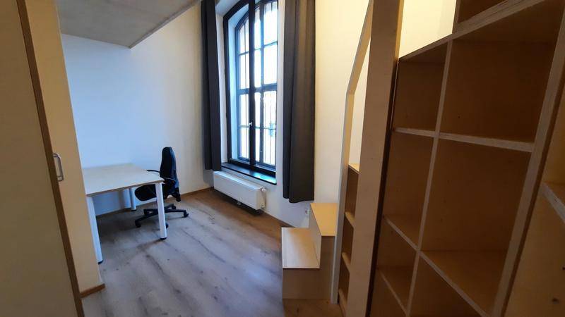 Funktionaler Arbeitsbereich mit Schreibtisch, großem Fenster und Holzregalen, Teil eines cleveren Raumkonzepts.