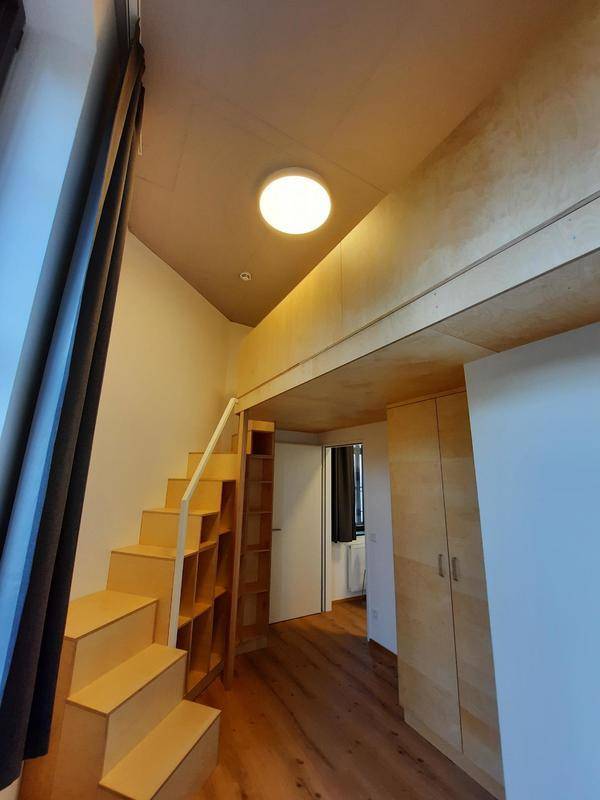 Heller Raum mit cleverem Hochbett-Design, Holztreppe und integrierten Stauräumen, ideal für Studenten.
