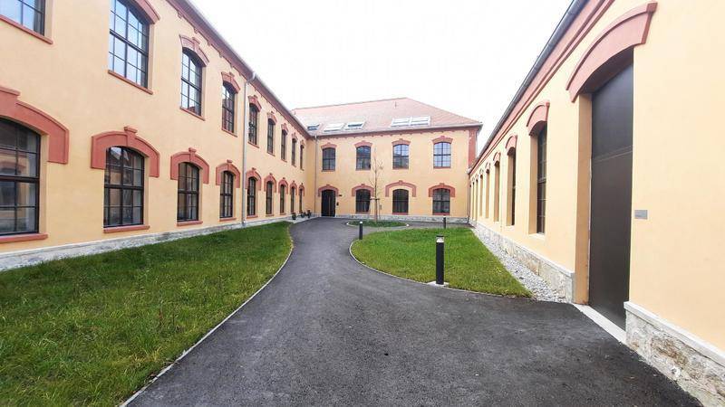 Innenhof eines Gebäudekomplexes mit gepflegter Rasenfläche und Gehwegen.