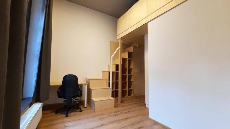 Schlafzimmer mit Hochbett auf einer Galerie, integriertem Schreibtisch und Holztreppe.