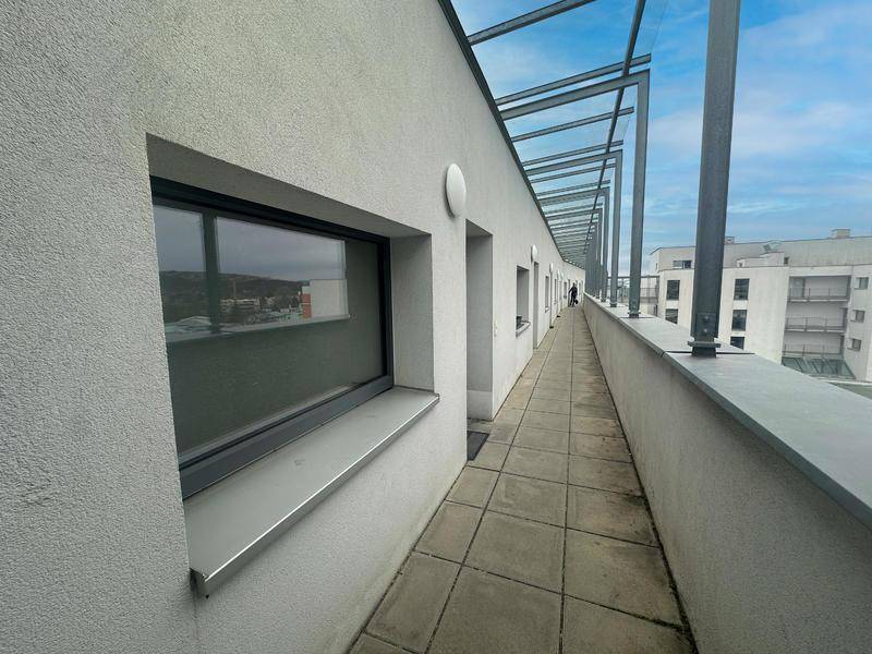 Langer, schmaler Zugangsbereich oder Terrasse mit Fliesenboden und Blick auf die Umgebung.