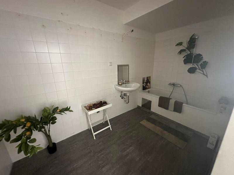 Badezimmer mit weißen Fliesen, Badewanne und Waschbecken, bereit zur individuellen Gestaltung.