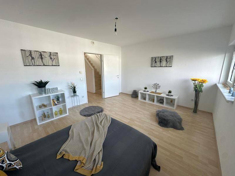 Helles Schlafzimmer mit Zugang zum Treppenhaus, Laminatboden und schlichter Dekoration.