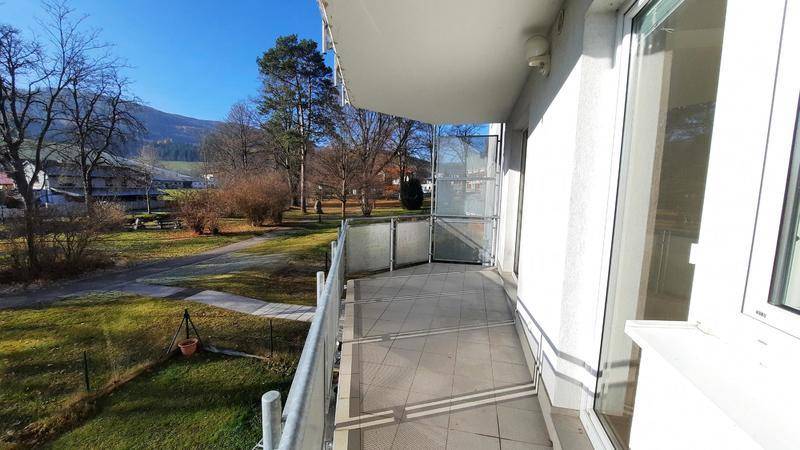 Heller Balkon mit Fliesenboden und weitem Blick ins Grüne und auf die Berge.