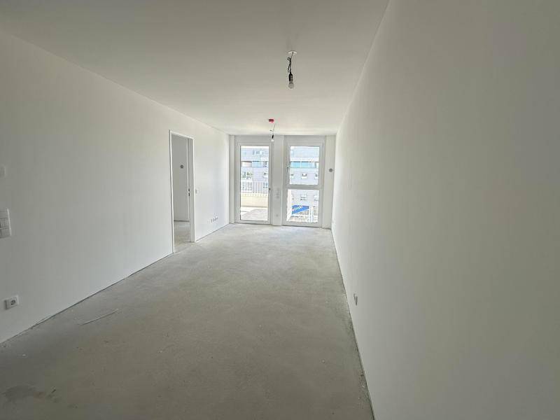 Heller, leerer Raum mit weißen Wänden und Betonboden, bereit für den Ausbau.