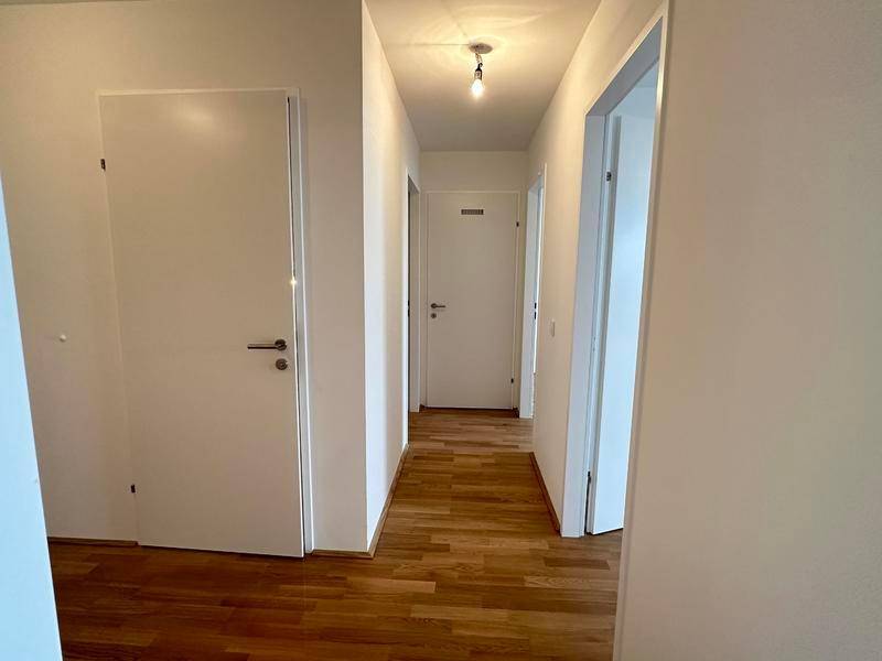 Langer, heller Flur mit Holzboden und mehreren Türen zu den angrenzenden Zimmern.