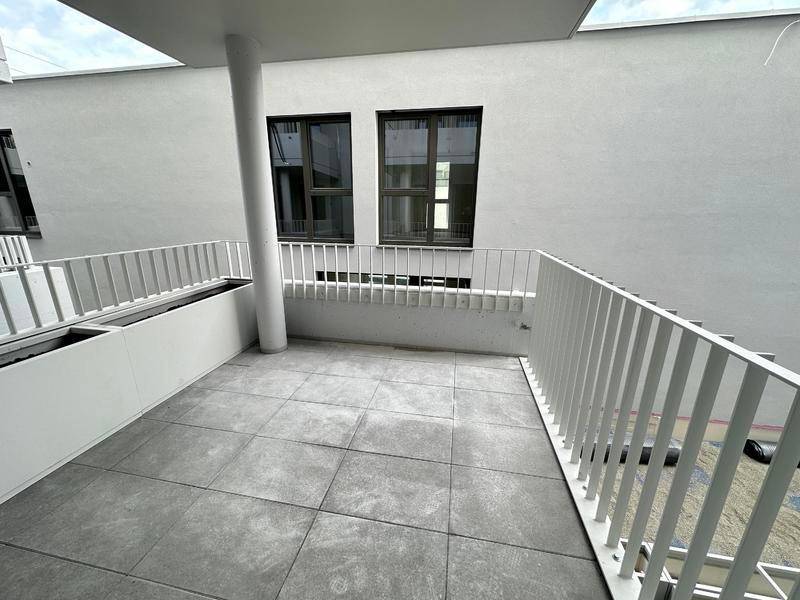 Moderner Balkon mit Fliesenboden und Blick auf die umliegenden Gebäude.