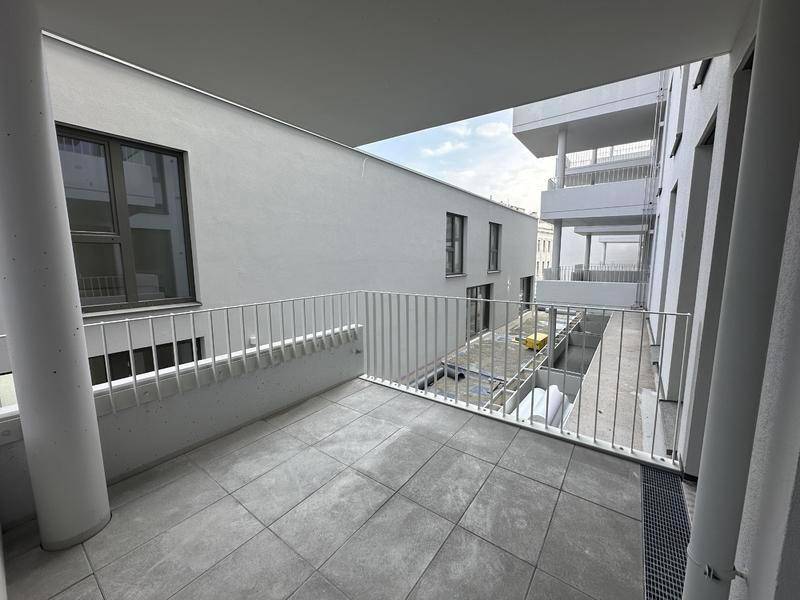 Geräumiger Balkon mit Fliesenboden und Blick auf den Innenhof des Gebäudes.