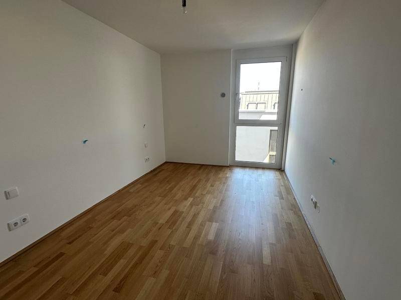 Helles Zimmer mit Holzboden und großem Fenster, ideal als Schlaf- oder Arbeitszimmer.