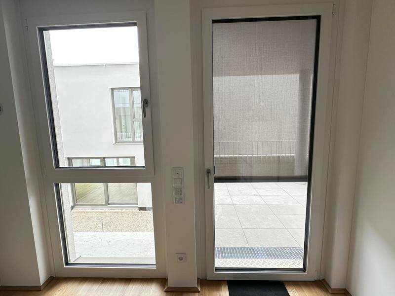 Fenster und Balkontür mit Blick auf den Außenbereich und die umliegenden Gebäude.