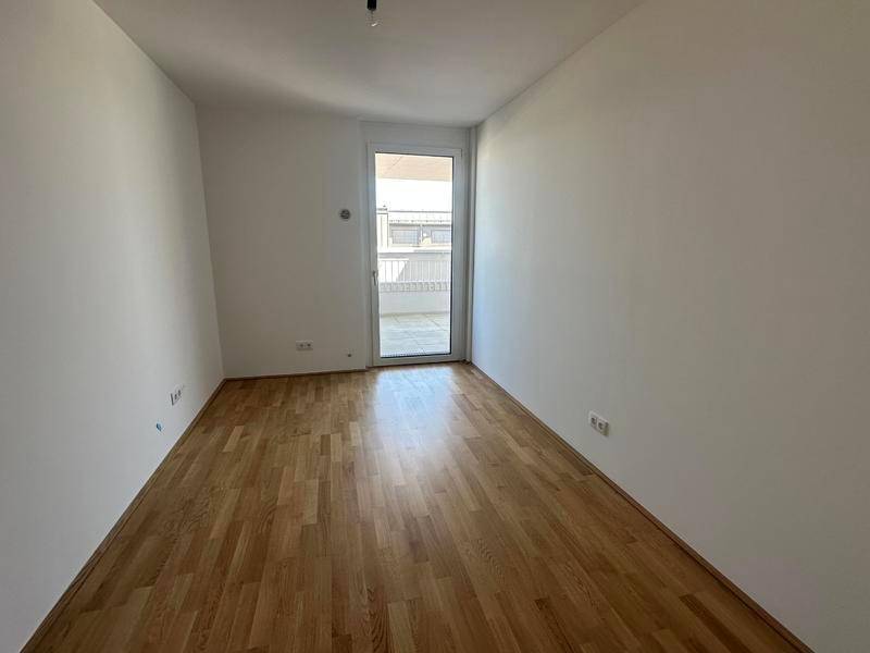 Leeres Schlafzimmer mit Holzboden und direktem Zugang zu einem Außenbereich.