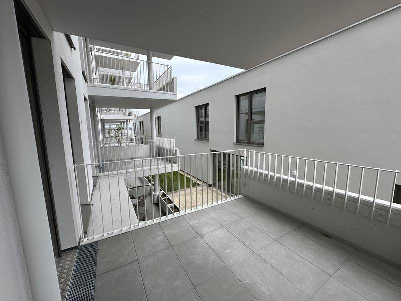 Geräumiger Balkon mit Fliesenboden und Blick auf den Innenhof des Gebäudes.