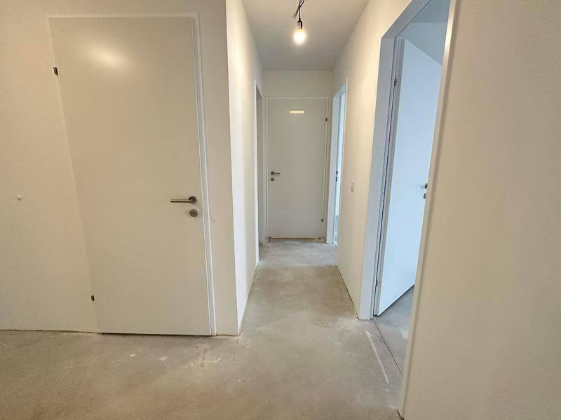 Heller Flur mit weißen Türen, Betonboden und schlichtem, modernem Design.