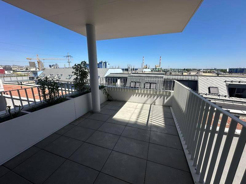 Geräumige Dachterrasse mit Fliesenboden, modernen Pflanzgefäßen und weitem Blick über die Stadt.