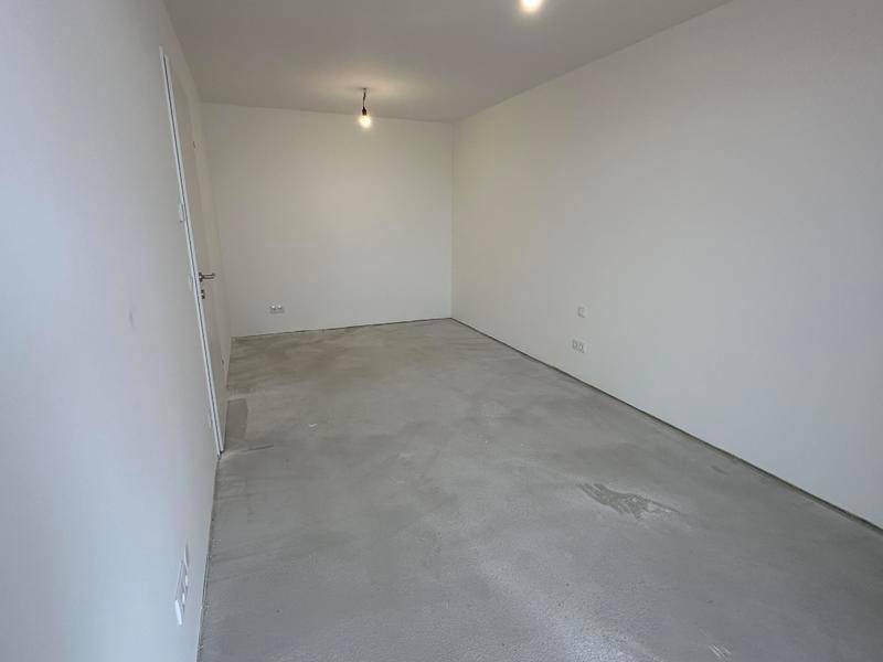 Leeres Zimmer mit Rohbetonboden und weißen Wänden, bereit für die persönliche Einrichtung.