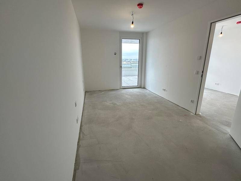 Heller Raum mit Rohbetonboden und Zugang zu einem Balkon, ideal für individuelle Gestaltung.