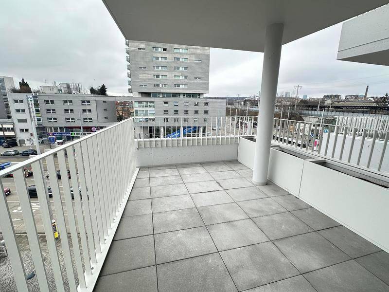 Geräumiger Balkon mit Fliesenboden und Blick auf die Stadt, ideal für entspannte Momente im Freien.