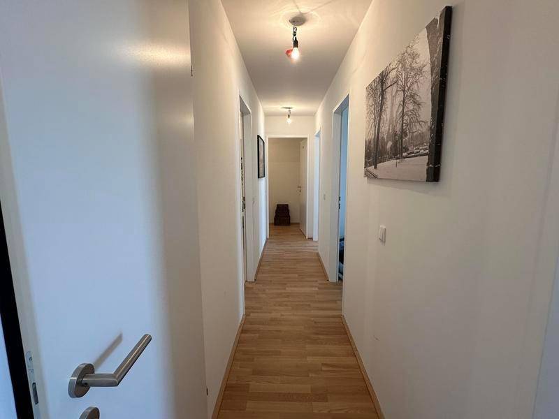Langer, heller Flur mit Holzboden, der zu den verschiedenen Räumen führt.
