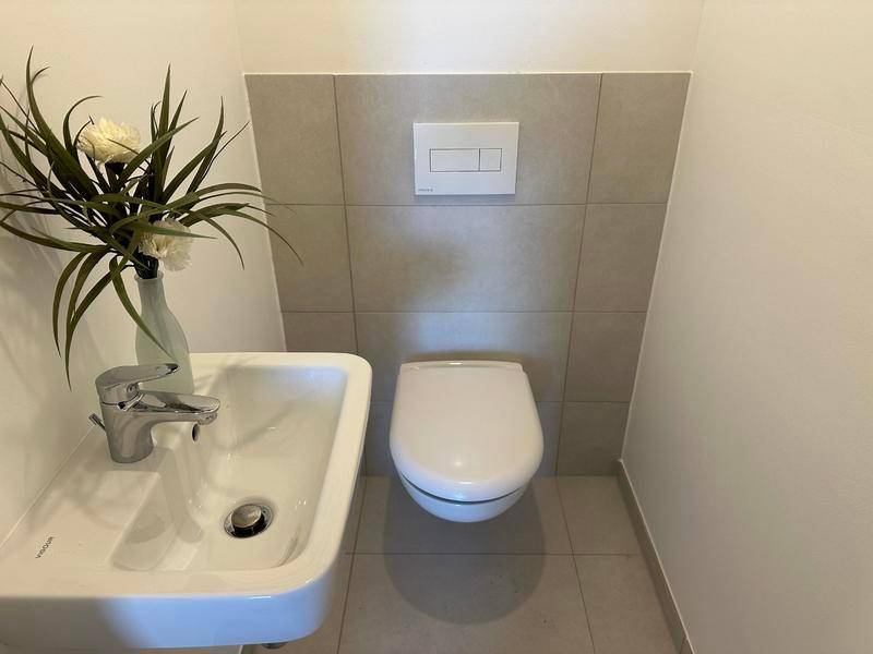 Separates Gäste-WC mit Wand-WC und kleinem Handwaschbecken.