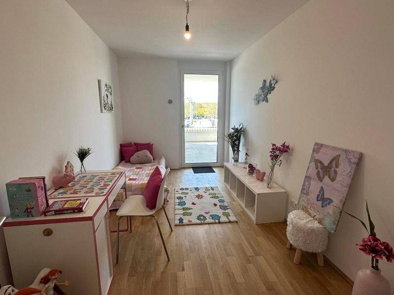 Helles Kinderzimmer mit Holzboden und Zugang zu einem Außenbereich.