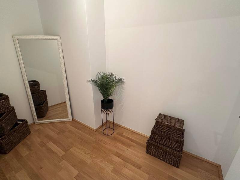 Kleiner Raum mit Holzboden und einem großen Spiegel, ideal als Abstellraum.