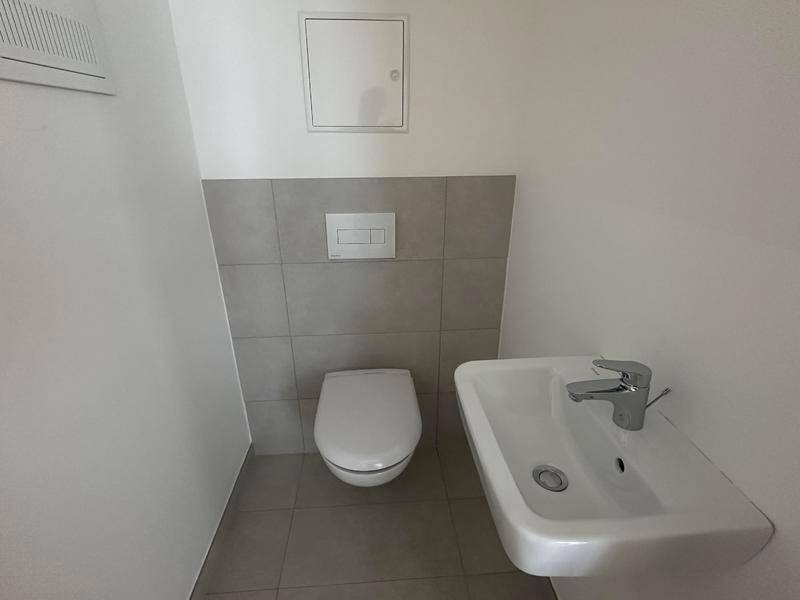 Kleines Gäste-WC mit wandhängendem WC und modernem Waschbecken, in hellen Tönen gehalten.