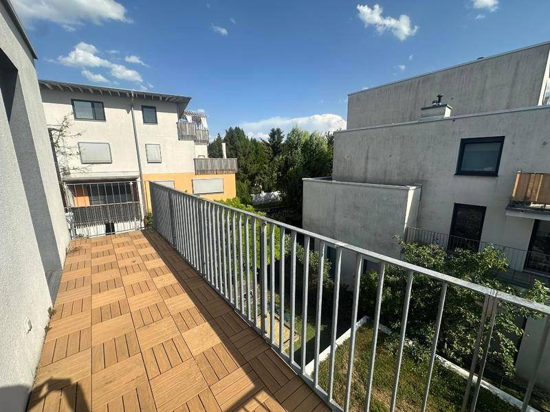 Geräumiger Balkon mit Holzbodenfliesen und freiem Blick auf die Nachbarschaft.