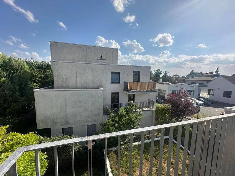 Ansicht des modernen Gebäudes von einem Balkon aus, mit weiteren Balkonen und grüner Umgebung.