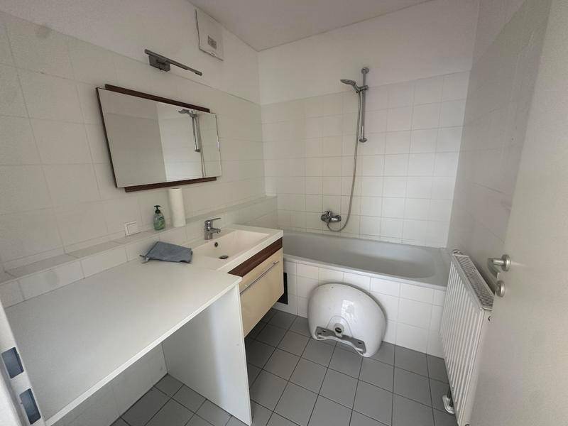 Funktionales Badezimmer mit Badewanne, Waschbecken und Fliesen an Wänden und Boden.