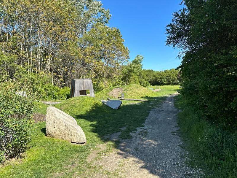 Weitläufiger Spielbereich mit natürlichen Materialien und viel Grün für Kinder.